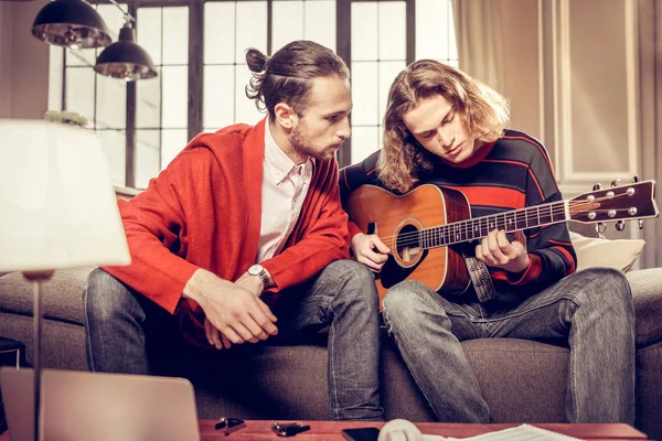 Dark-haired gitaar leraar zijn leerling beluisteren met baard — Stockfoto