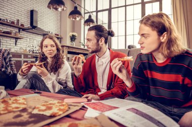 Şirket öğle yemeği için lezzetli pizza yemek üç genç müzisyenler