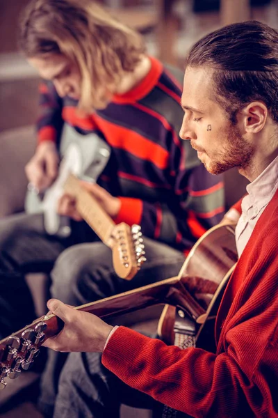Músico con un pequeño tatuaje en la cara tocando la guitarra — Foto de Stock