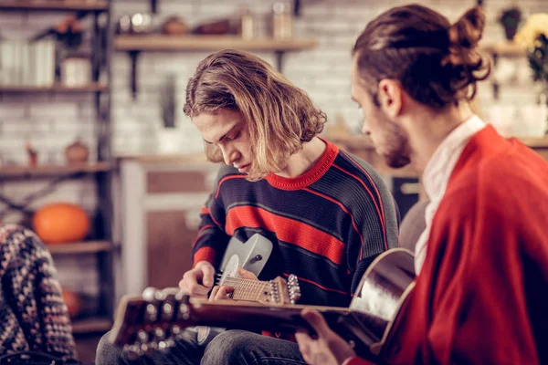 Joven con suéter a rayas aprendiendo a tocar la guitarra — Foto de Stock