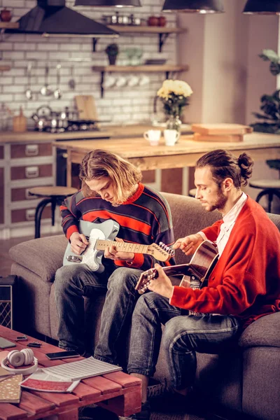 Bandmitglieder sitzen auf Sofa und spielen Musikinstrumente — Stockfoto