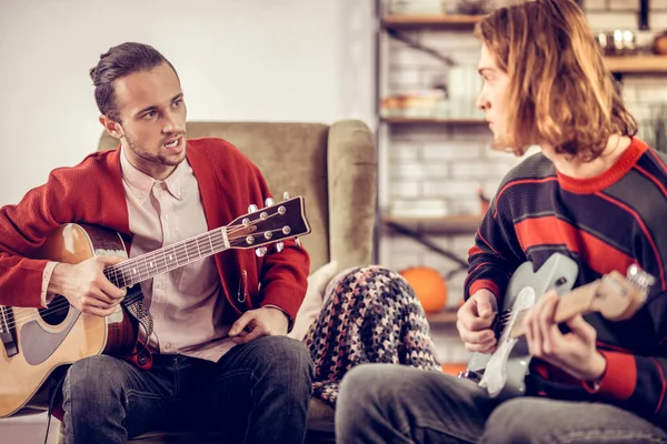 Gitarrenlehrer sitzt im Sessel und spricht mit seinem Schüler — Stockfoto