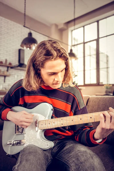 Student with bob cut getting satisfaction playing the guitar