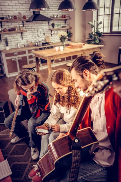 Hermano y hermana escuchando a su tutor privado de guitarra enseñándoles — Foto de Stock