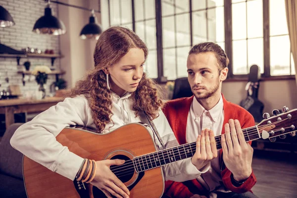 Tienermeisje ongerust gevoel tijdens het spelen van de gitaar in de buurt van haar leraar — Stockfoto