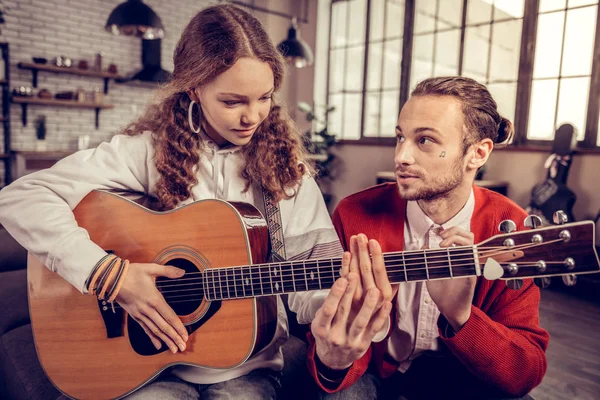 Broer helpt zijn schattige tiener zus gitaar spelen — Stockfoto