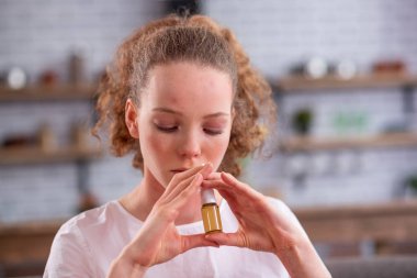 Burun ile ilaç dolum kıvırcık saçlı genç kadın