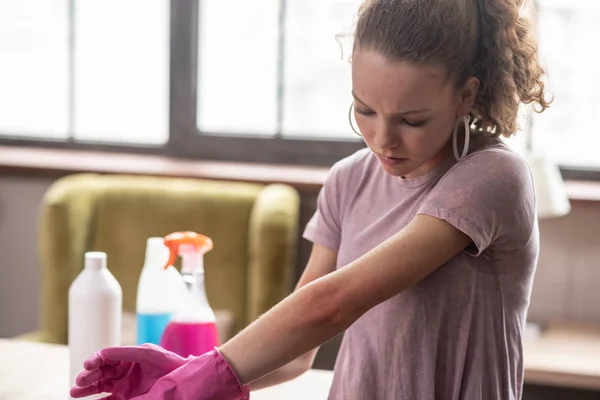 Verward krullend vrouw aandachtig observeren van haar hand — Stockfoto