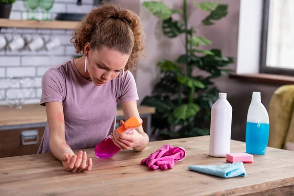 Menina irritada atenta lendo ingredientes de spray de limpeza — Fotografia de Stock