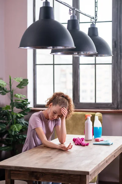 Depressed long-haired girl leaning on table and observing irritation — Stock Photo, Image