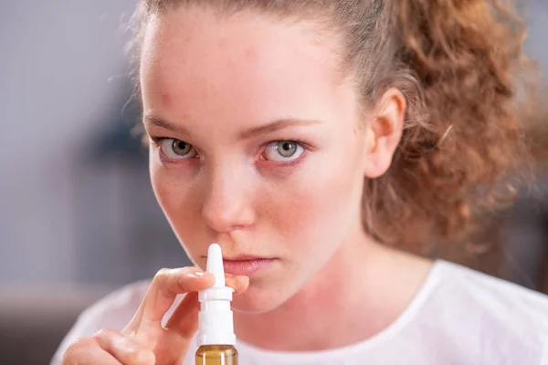 Beautiful young lady with light green eyes spraying medicine — Stock Photo, Image