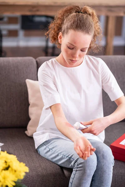 Attentive curly woman covering her allergic irritation on hand — Stock Photo, Image