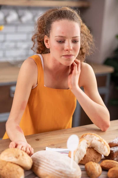 Unpleasant good-looking young lady leaning on kitchen table and rubbing her neck — Stock Photo, Image