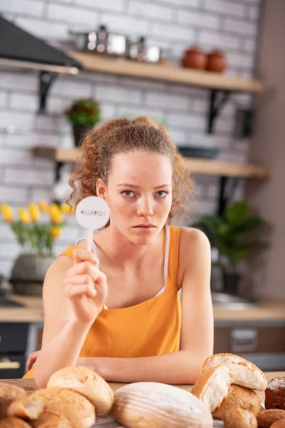 Miserable young woman with light eyes leaning on wooden table — Stock Photo, Image
