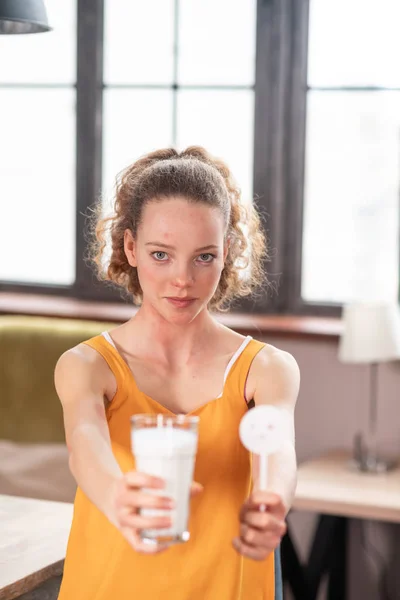 Perturbe a mulher de cabelos encaracolados que apresenta leite sem lactose nas mãos — Fotografia de Stock