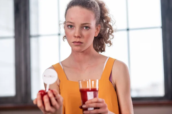 Mulher em top amarelo brilhante carregando mini tomates e vidro cheio de suco — Fotografia de Stock