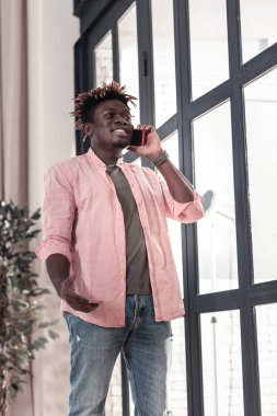 Büyük pencere yakınındaki neşeli esmer erkek ayakta