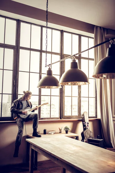 Rockmuzikant zit in de buurt van venster en componeren van nieuwe lied — Stockfoto