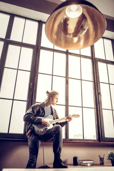 Langhaariger Rockmusiker, der sich beim Musizieren erstaunlich fühlt — Stockfoto