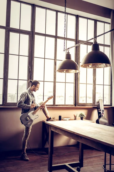 Bärtiger dunkelhaariger Musiker steht und spielt Rocksong — Stockfoto