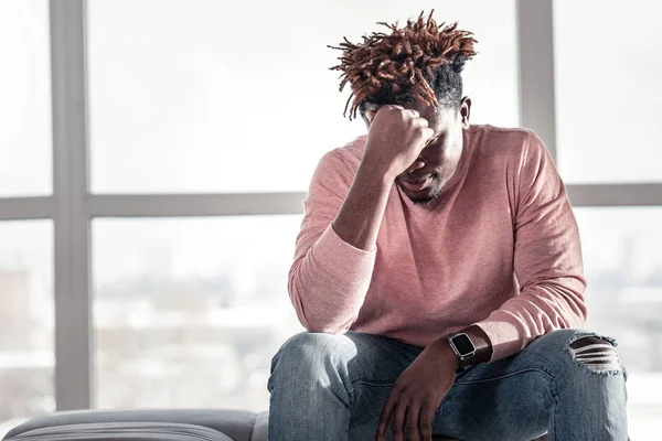 Doordachte donkere man zit op de gezellige sofa — Stockfoto