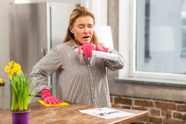 Mujer limpiando mesa y estornudos teniendo alergia al polvo — Foto de Stock
