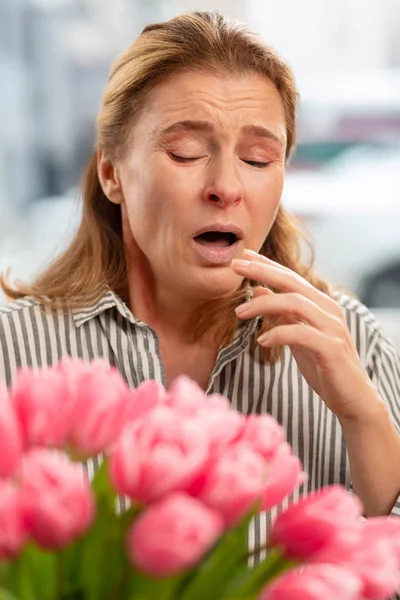 Mulher espirrando depois de cheirar flores com alergia — Fotografia de Stock