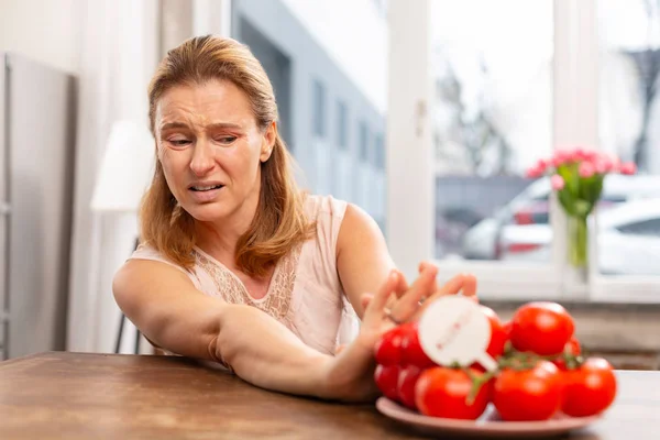 Σκοτεινός-eyed ώριμη γυναίκα δεν τρώει τομάτες, ενώ αίσθηση αλλεργικές — Φωτογραφία Αρχείου
