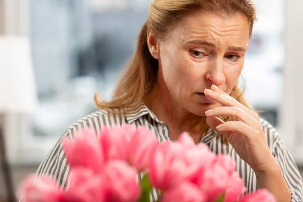 Alte Frau mit Gesichtsfalten, die sich schlecht fühlt, wenn sie eine Allergie gegen Tulpen hat — Stockfoto