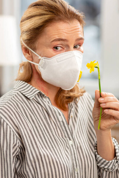 Женщина в маске на лице с аллергией на цветы
