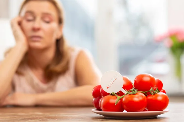 Donna guardando il piatto con pomodori ma avendo sensibilità — Foto Stock