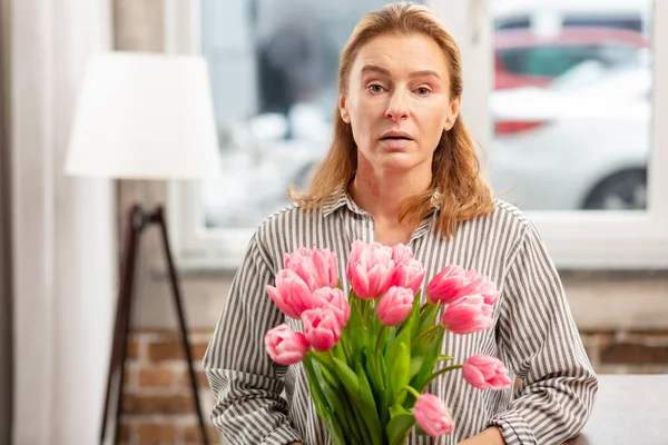 Vrouw met roze bloemen gevoel gevoelig voor bloei — Stockfoto