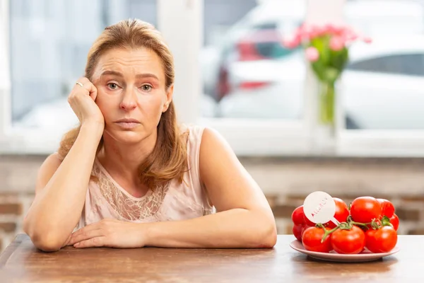 Reife blondhaarige Frau sitzt am Tisch und hat eine Nahrungsmittelallergie — Stockfoto