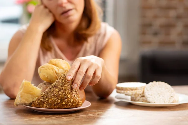 Mujer alérgica al gluten tomando pequeño bollo con semillas —  Fotos de Stock