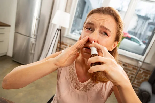 Mujer de pelo rubio usando spray nasal estornudando después de la alergia — Foto de Stock