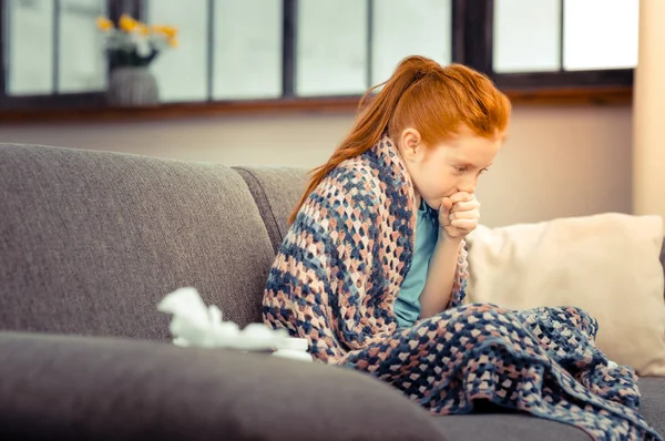 Unhappy red haired girl coughing in her hand — Stock Photo, Image