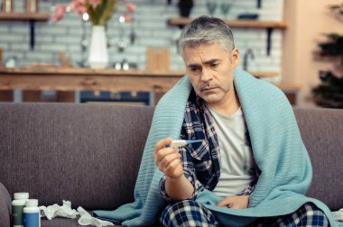 Mutsuz kasvetli adam termometre bakıyor