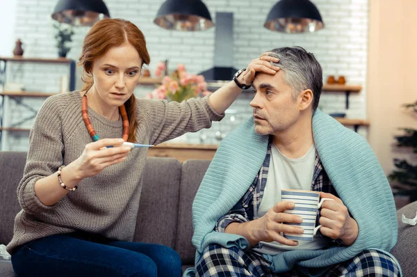 Nette besorgte Frau beim Blick auf das elektronische Thermometer — Stockfoto