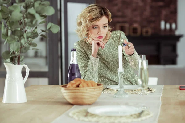 Förtvivlad flickvän sitter vid bord med alkohol och croissanter ensam — Stockfoto