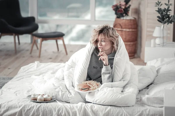 Woman eating junk food in her bed after breakup with boyfriend — Stock Photo, Image