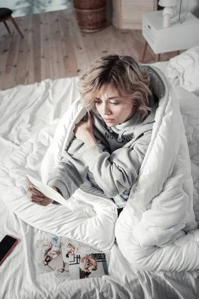 Женщина сидит в постели и чувствует себя сентиментальной после разрыва — стоковое фото