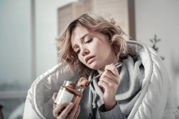 Young unhappy woman eating chocolate paste feeling stressed — Stock Photo, Image