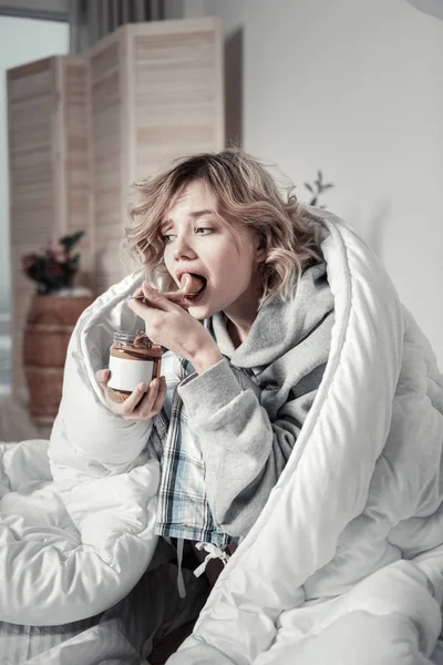 Mujer comiendo demasiados dulces en la cama sufriendo de depresión — Foto de Stock