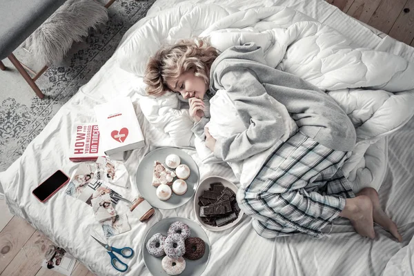 Mujer acostada en la cama cerca de libros y comida después de la ruptura — Foto de Stock