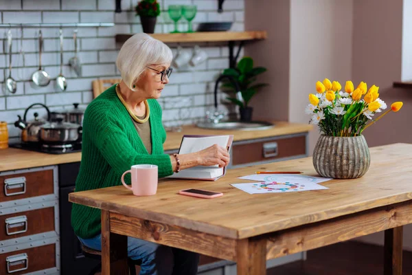 Berörda silver-haired kvinna i glasögon att vrida recept boksidor — Stockfoto