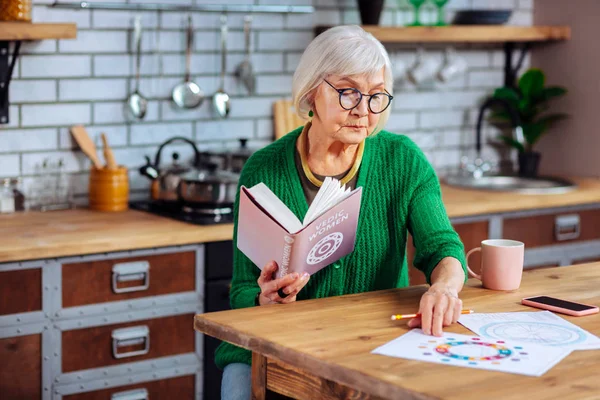 Senhora idosa encantadora não distraída estudando gráficos védicos e livro — Fotografia de Stock