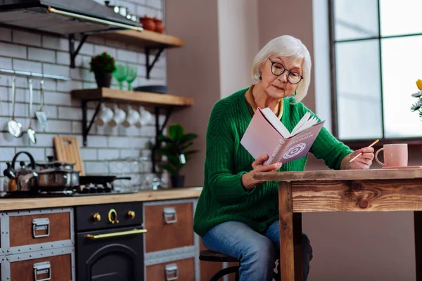 Dama de pelo blanco inteligente en años haciendo notas de libros védicos — Foto de Stock