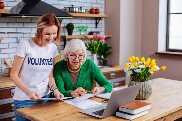 Encantador voluntario social mostrando la presentación del préstamo pensionista en el ordenador portátil — Foto de Stock