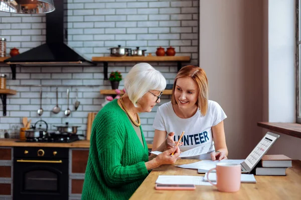 Social department employee assisting grey-haired female with social documents.