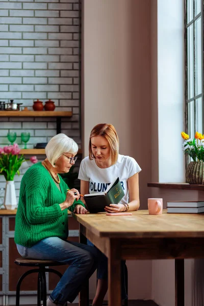 Genç-yetişkin kadın ile gümüş saçlı dini emekli dame İncil kitap okuma — Stok fotoğraf